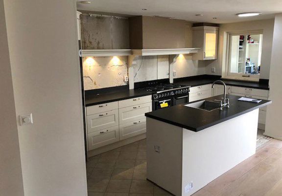 Keukenverbouwing met kookeiland, crème kasten en zwart werkblad in Haarlem