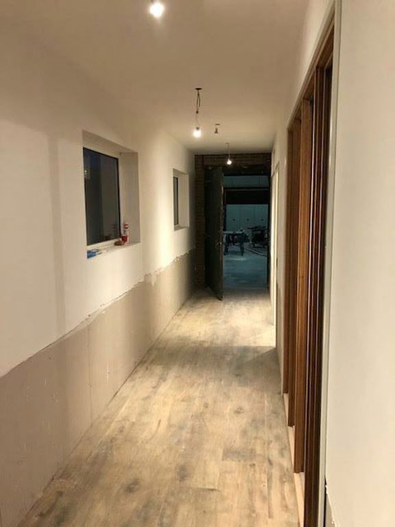 Gang van kantoor tijdens renovatie met houten vloer en binnenramen in Spierdijk