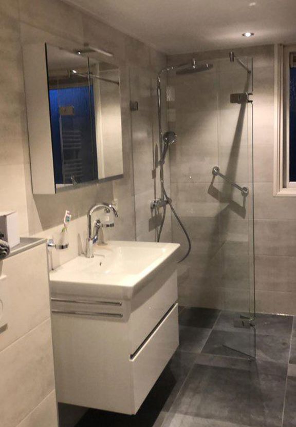 Badkamer met glazen douchewand, regendouche en wastafelmeubel in Hoorn