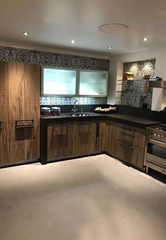 Hoekkeuken met houten kasten, glazen bovenkasten en decoratieve tegelwand in Bloemendaal