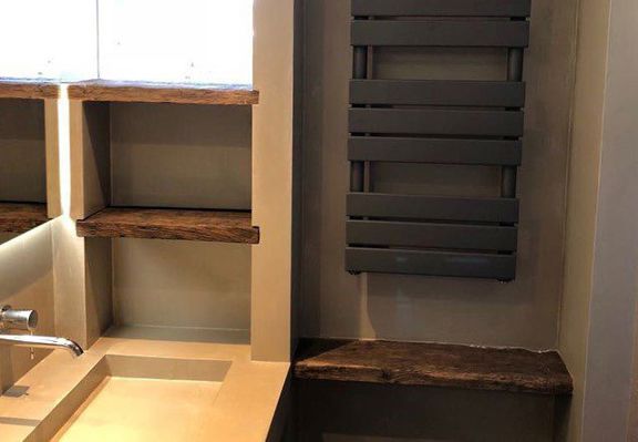 Zwarte handdoekradiator en houten wandplanken in gerenoveerde badkamer in Hoorn