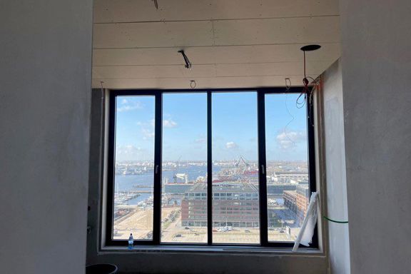 Penthouse in aanbouw met groot raam en uitzicht over het IJ in Amsterdam